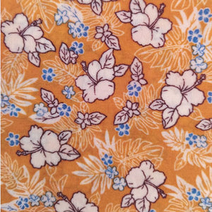 Bee wrap avec pour motif des fleurs et pistils blancs et des petites fleurs bleues sur fond de couleur curcuma