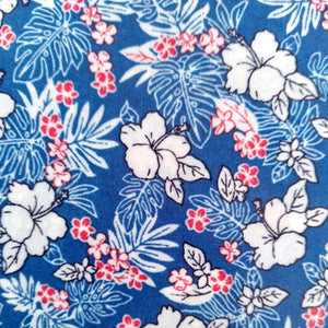 Bee wrap avec pour motif des fleurs blanches tahitiennes et des feuilles transparentes avec des petites fleurs roses sur fond bleu ciel